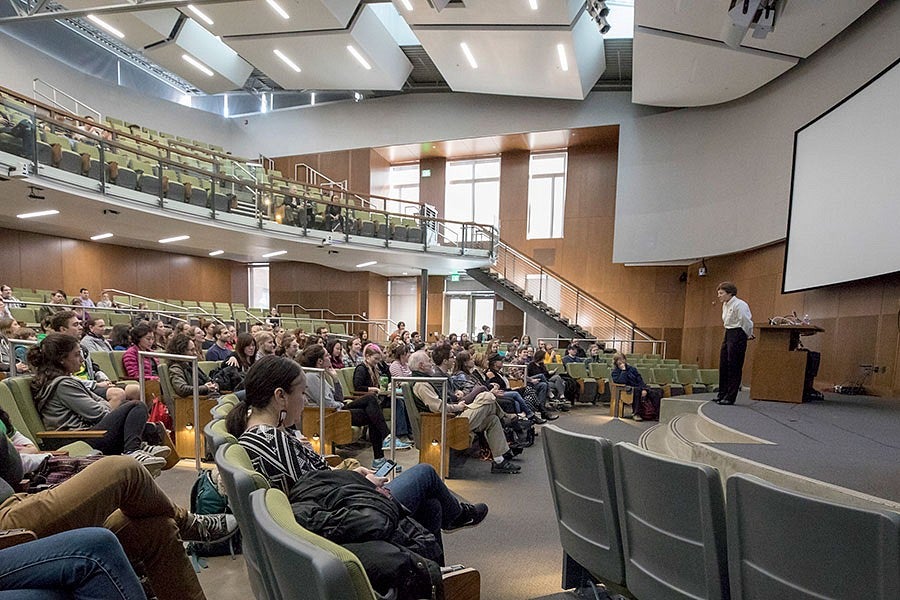 an audience listens to a presentation in a lecture hall